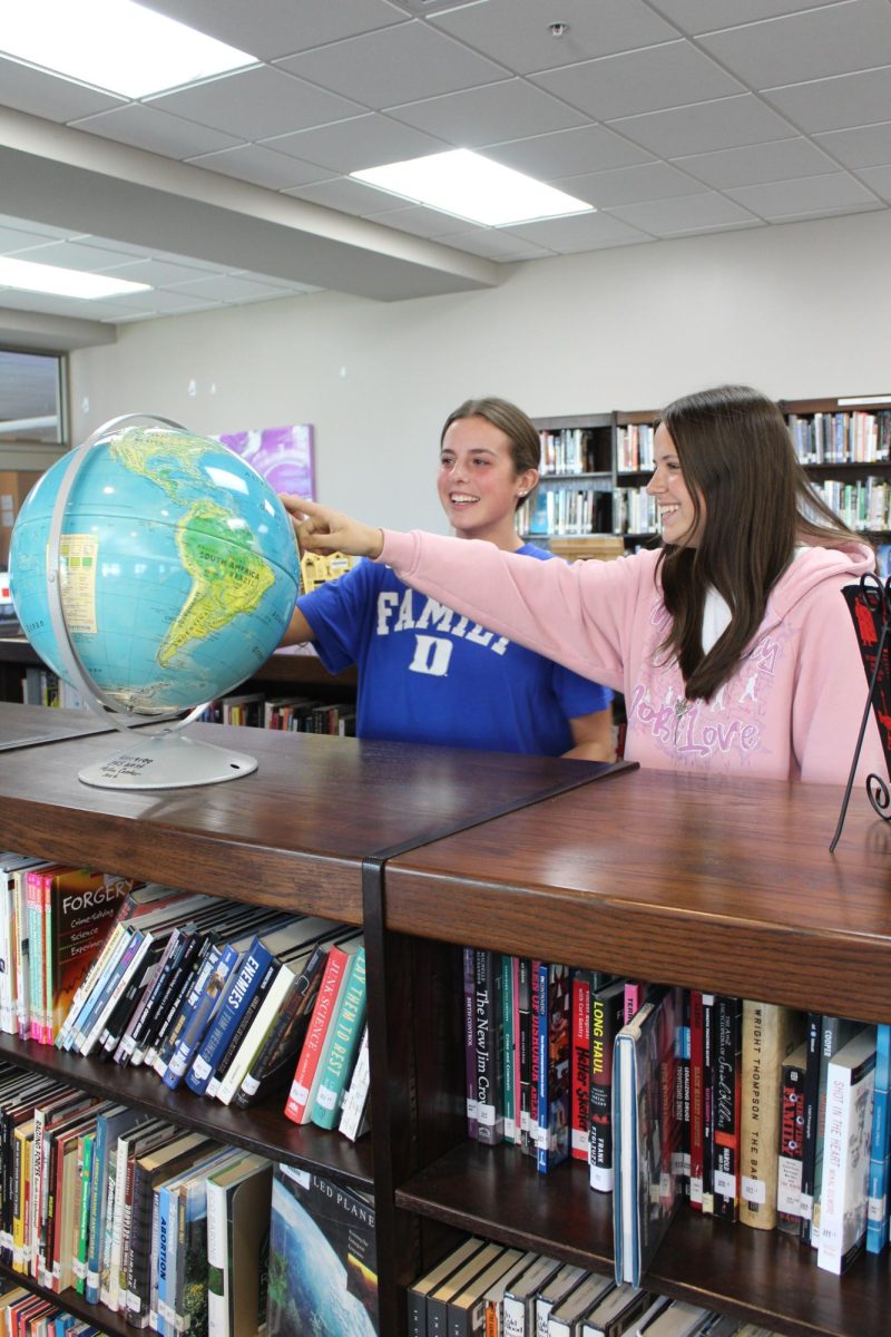 Mieke Kleinbongardt and her friend Anna Smith laugh while pointing out where Kleinbongardt is from on the globe. 